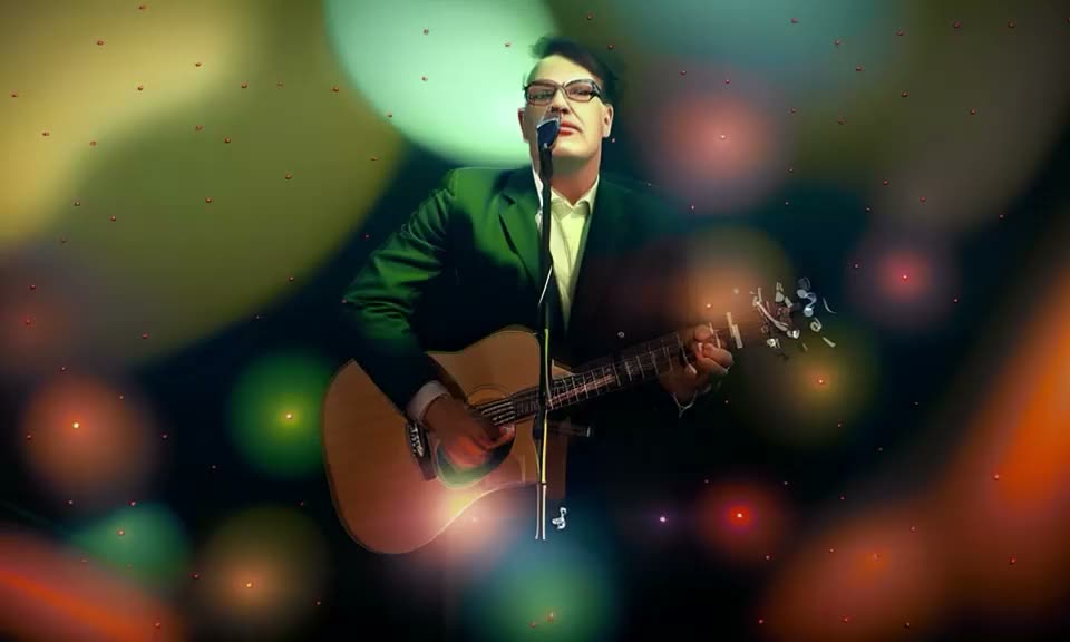 Tony performing in a suit under green and amber stage lights